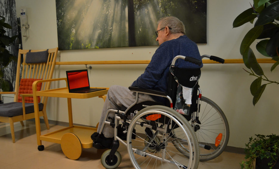 Old man sitting on a wheel chair and having a video call.