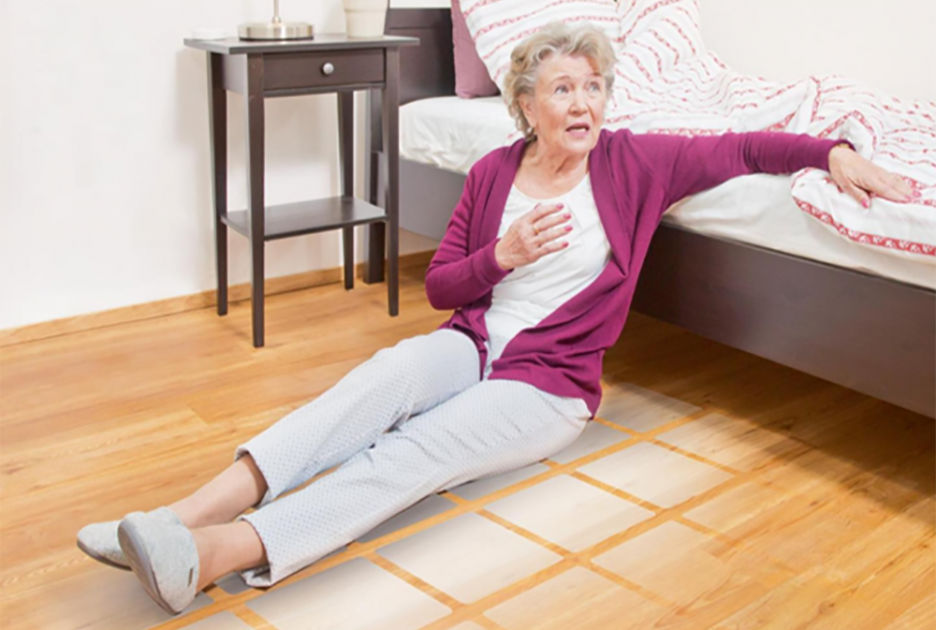 Woman sitting on a floor next to bed