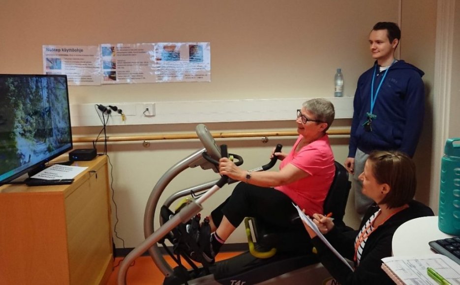 A woman using the exercise software and two students watching her.