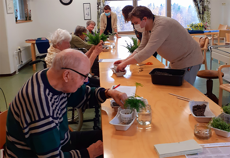 elderly people and students around the table working with plants